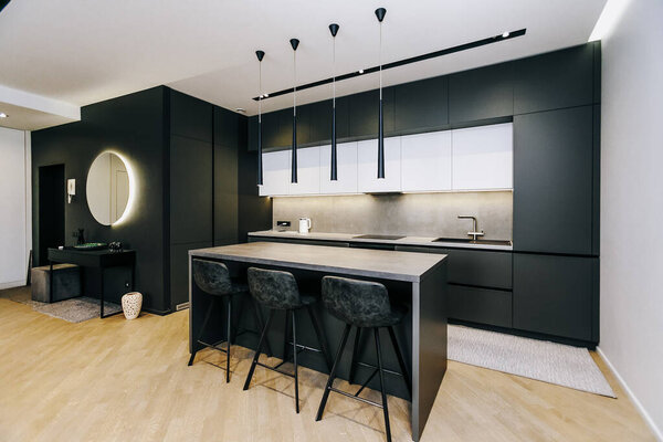 Эта современная кухня имеет элегантные черные шкафы и гладкие стулья бар, идеально подходит для современной жизни