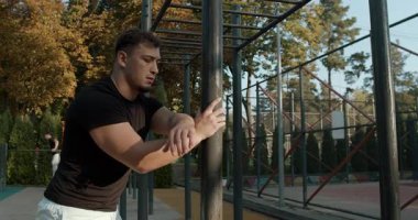 A man performs a stretching exercise at an outdoor fitness area, showcasing his dedication to fitness.