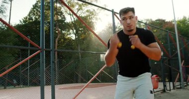 A dedicated athlete energetically practicing various boxing moves during a sunset workout on a tennis court