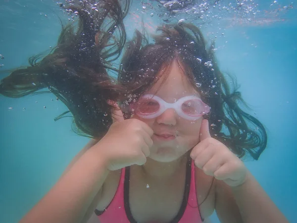 Close Up of Young Girl Doing the Thumbs Up Under Water while Swimming