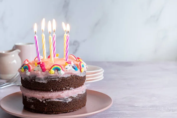 Chocolate Birthday Cake Decorated with Raspberry Frosting and Unicorns and Rainbows with Six Birthday Candles - Horizontal with Copy Space