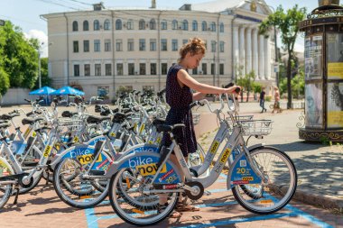 Genç ve güzel bir kız turistik merkezde bir sokak bisikletine biniyor.