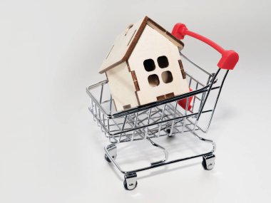 İpotek konsepti. Emlak satın almak. Oyuncak alışveriş arabası olan ahşap bir evin küçük bir modeli..