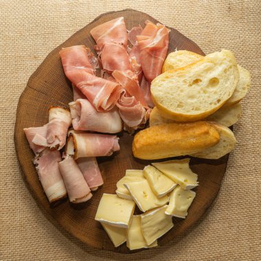 Şarap aperatifi. Jambon, Parma jambonu, baget, ahşap tezgahta peynir.