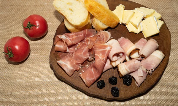 Wine appetizer. Ham, Parma ham, baguette, Cheese on a wooden stand. — Stock Photo, Image