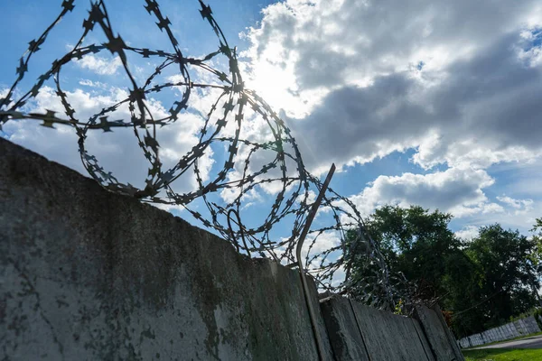 Beton bir çitin üzerindeki dikenli teller gökyüzüne karşı. Korunaklı bölge. tek renkli fotoğraf.