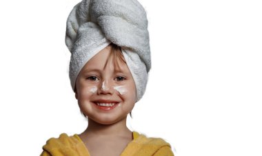 Yanaklarında beyaz krema olan sarı bornozlu tatlı kız.