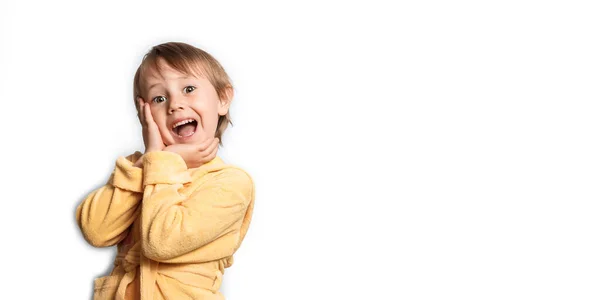 Pequena menina bonito em um roupão de banho amarelo posando engraçado em um fundo branco . — Fotografia de Stock