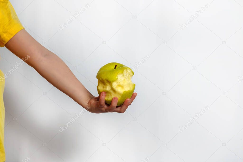 Green bitten apple in child hand on white