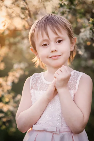 Linda niña r al lado de un manzano en flor al atardecer —  Fotos de Stock