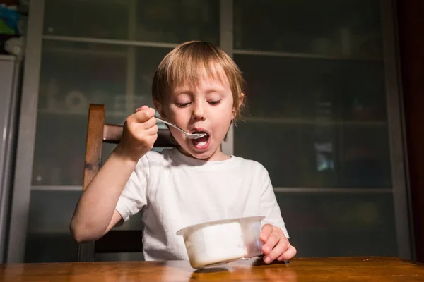 Menina adorável comendo queijo cottage de colher, lanche de leite saudável . — Fotografia de Stock