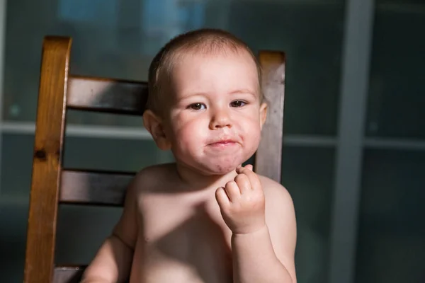 Adorable baby boy eating cottage cheese from spoon, healthy milk snack.