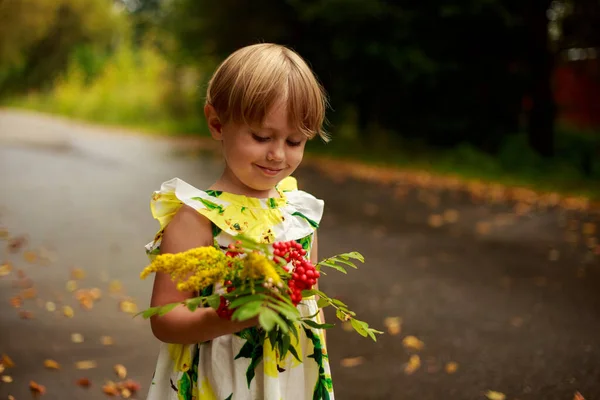 Niña rubia en un vestido colorido con una lata de riego amarillo sonriendo —  Fotos de Stock