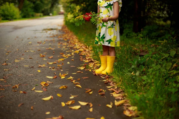 Menina loira em botas amarelas na poça — Fotografia de Stock