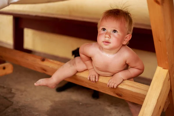 Kleiner süßer Junge unter dem Holztisch im Freien — Stockfoto