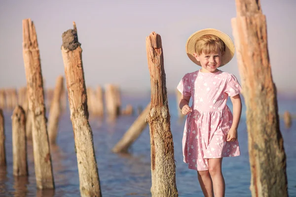 Chica de pie en madera muy viejo podrido encallar en la playa — Foto de Stock