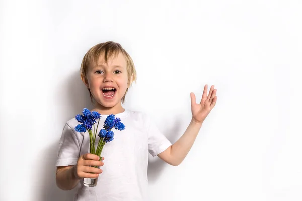 Porträtt av det vackra barnet håller en bukett blå blommor för sin mor. — Stockfoto