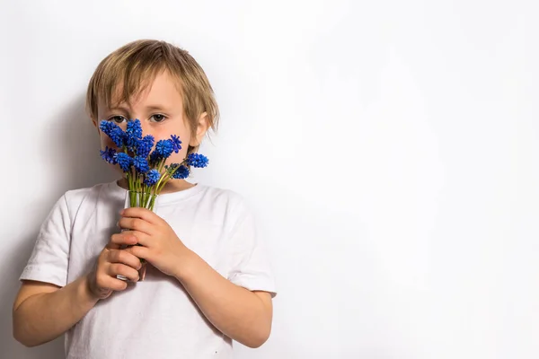 Retrato da bela criança segura um buquê de flores azuis para sua mãe . — Fotografia de Stock