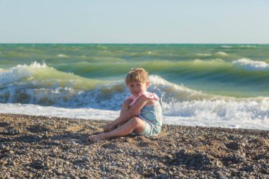 Boş bir çakıl taşı kumsalında güzel bir kız denize doğru bakıyor.. 