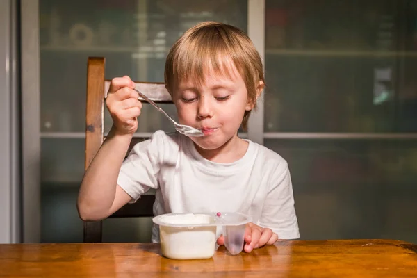 Menina adorável comendo queijo cottage de colher, lanche de leite saudável . — Fotografia de Stock