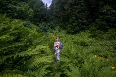 Sırt çantasında çocukla dağlarda yürüyüş yapan bir yürüyüşçü kadın. . 