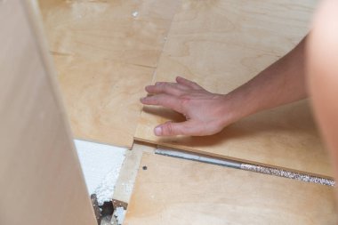 Tavan arasında bir kontrplak parçası tutuyor.