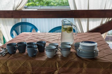 Tahta bir verandadaki masada limonata ve gözlüklü bir sürahi.