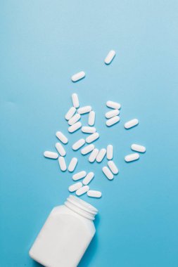 İlaç şişesinden dökülen beyaz ilaç hapları ve haplar. Yukarıdan aşağıya makro 