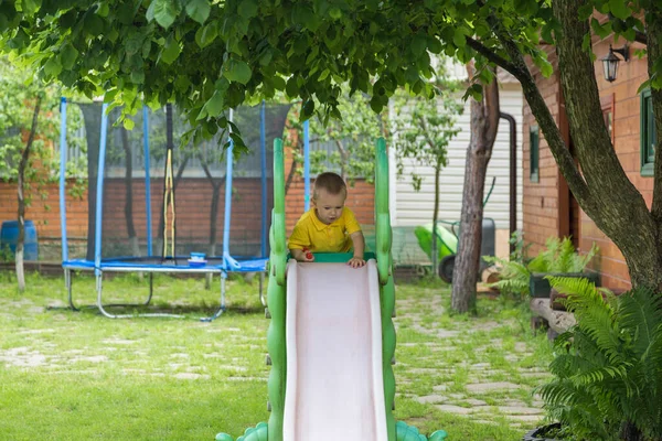 En liten pojke rullar utför på gården. — Stockfoto