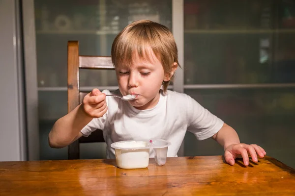 Menina adorável comendo queijo cottage de colher, lanche de leite saudável . — Fotografia de Stock