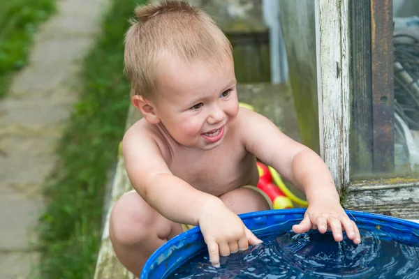 A boy plays with water in the water barrel in the garden Royalty Free Stock Photos