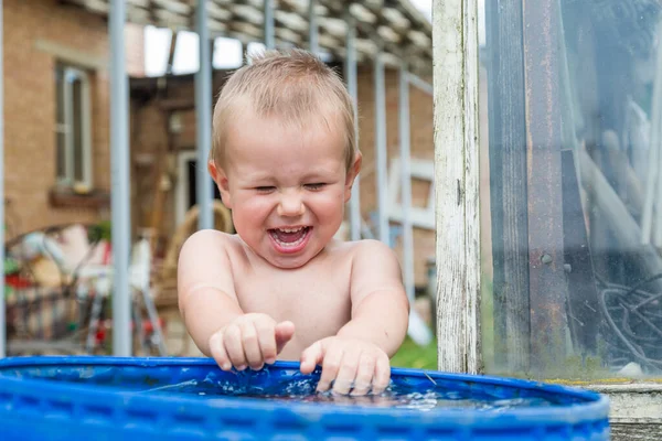 Bir çocuk ellerini su varilinde yıkıyor.