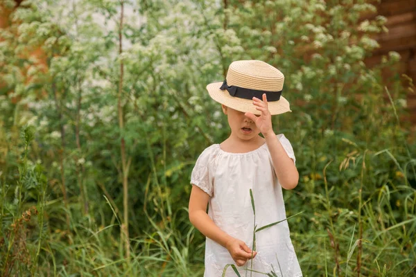 Niña en un vestido boho blanco con hermosos matorrales verdes de hierba . — Foto de Stock