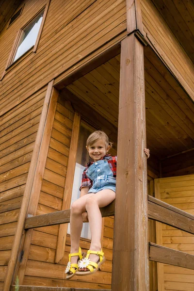 Söt liten flicka i cowboyhatt, klädd i jeansshorts och röd vit skjorta — Stockfoto