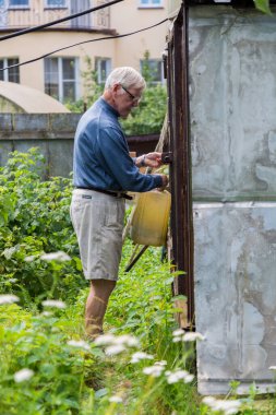 Mutlu son sınıf öğrencisi bahçede çiçekleri suluyor.