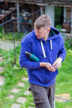 Bir adam bir köy evinin çatısında dururken elinde bir tornavida tutuyor. Yeni polikarbonat tavan örtüsünü termal yıkama ile emniyete alıyorum.
