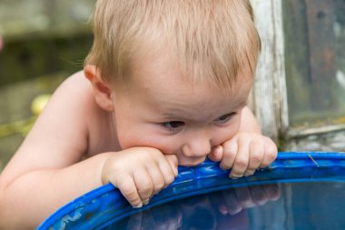 Bir çocuk su varilinden su içmeye çalışıyor.