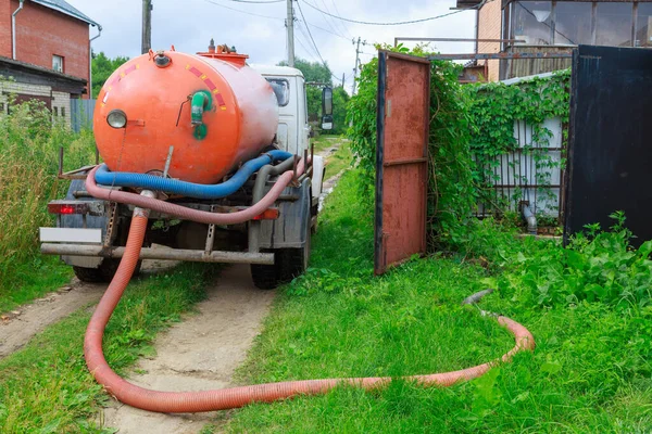 A Sewage truck working in village environment.