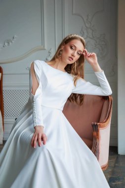 Saç stili ve şatafatlı bir gelinlikle düğüne hazırlanan bir gelin. Stüdyoda sarı saçlı ve mavi gözlü güzel bir kızın portresi.