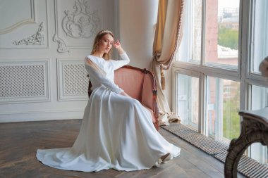 Saç stili ve şatafatlı bir gelinlikle düğüne hazırlanan bir gelin. Stüdyoda sarı saçlı ve mavi gözlü güzel bir kızın portresi.