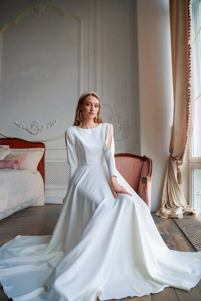 Невеста с прической и макияж в роскошном свадебном платье подготовки к свадьбе. Портрет красивой девушки с светлыми волосами и голубыми глазами в студии