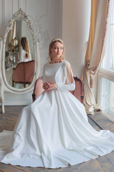 Невеста с прической и макияж в роскошном свадебном платье подготовки к свадьбе. Портрет красивой девушки с светлыми волосами и голубыми глазами в студии