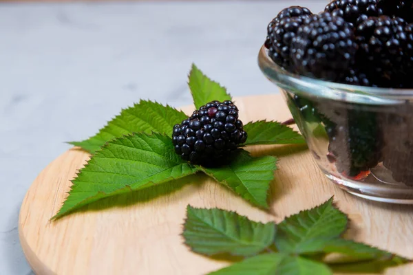 Ripe Blackberries Leaves Glass Bowl Bamboo Cutting Board Concrete Background — Stock Photo, Image