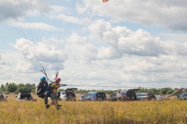 Tver, Rusya - 9 Ağustos 2020: Tandem Paragliding pistten kalkış. İnsanlar etrafta neler yapıyor. Arka planda bulutlu mavi gökyüzü görünür..