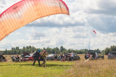 Tver, Rusya - 9 Ağustos 2020: Tandem Paragliding pistten kalkış. İnsanlar etrafta neler yapıyor. Arka planda bulutlu mavi gökyüzü görünür..