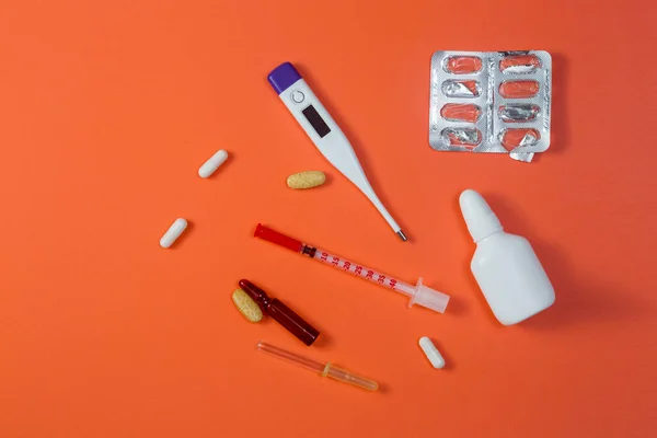 cold season is open. Cold medicines, pills, drops, pipette, thermometer on a solid background