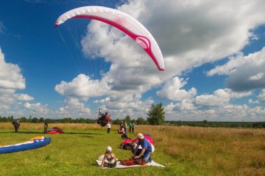 Tver, Rusya - 9 Ağustos 2020: Arka planda bulutlu mavi gökyüzü uçuşundan sonra paraşütle inmek görülüyor. Uçuşları seyreden insanlar.