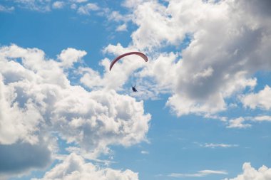Tver, Rusya - 9 Ağustos 2020: Bir paraglider bulutların arka planında mavi gökyüzünde uçuyor. Güneşli bir günde gökyüzünde paraşütle atlamak.