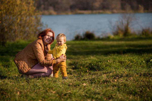 .Annesi sarı ceketli bebeğinin yanına çömelmiş ve kameraya bakmış. Altın sonbahar Hindistan yazı.