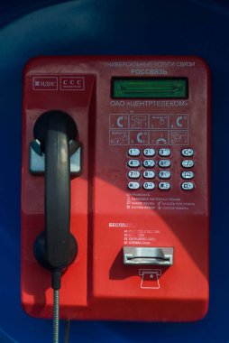 Tver, Rusya - 9 Ağustos 2020: Köy manzarasının arka planına karşı köy merkezinde düğmeli telli bir telefon kulübesi